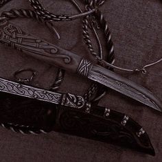 two knives are laying next to each other on a black surface with braids around them