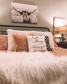 a bed that has some pillows on top of it and a cow painting above the headboard