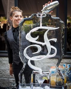 a woman standing next to an ice sculpture with the letter s on it's side