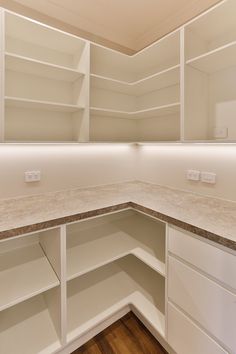 an empty kitchen with white cabinets and marble counter tops