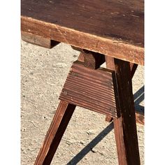 an old wooden table that has been stained brown and is sitting on the ground with no one around it