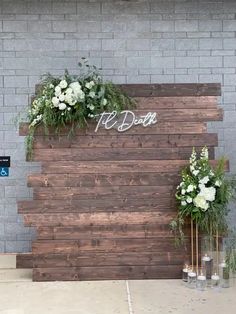 some white flowers and greenery are in vases on the side of a wall