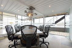 a table with chairs and a chandelier hanging from the ceiling in front of large windows