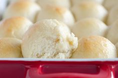 a red dish filled with rolls on top of a table