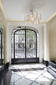 an ornate entryway with wrought iron doors and chandelier