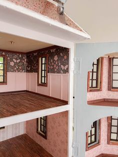 the inside of a doll house with pink walls and wood floors