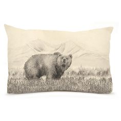 a black and white photo of a bear on a pillow with mountains in the background