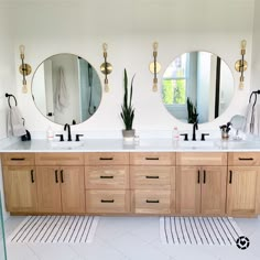 a bathroom with two sinks and three mirrors on the wall above them are plants in pots