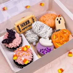 an open box filled with halloween cupcakes and candy