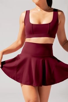 a woman wearing a maroon skirt and crop top