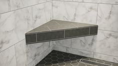 the corner of a bathroom with marble tile and hexagonal floor tiles on the walls