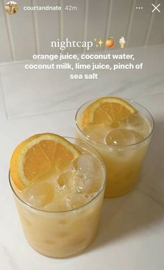 two glasses filled with orange juice sitting on top of a white counter next to each other