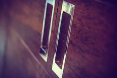 two glass doors on the side of a wooden cabinet with metal handles and knobs