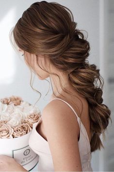 a woman holding a large white hat with roses in it