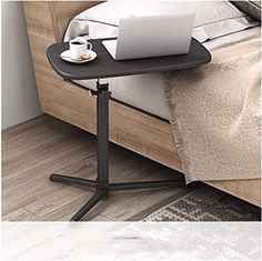 a laptop computer sitting on top of a table next to a bed