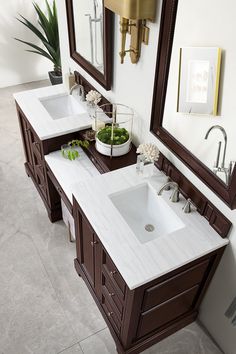 two sinks and mirrors in a bathroom with white tiles on the floor, along with potted plants