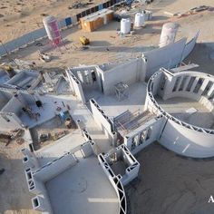 an aerial view of a building being built in the middle of desert area with construction equipment around it