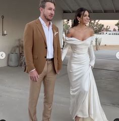 a man and woman standing next to each other in front of a white building with an open door