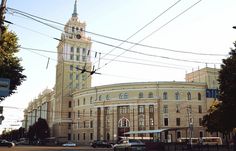 an old building with a clock tower in the center and cars parked on the street