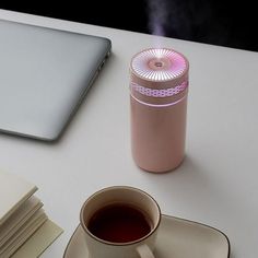 a cup of tea next to a laptop on a white table with papers and notebooks