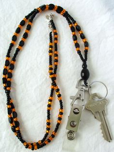 Orange & Black Beaded Lanyard This Orange & Black Beaded Lanyard can be used as a badge holder, an I.D. holder, keychain necklace, watch holder - it's a multi-use accessory for home or office! 34" in length, long enough to put on or remove overhead. It also has an easy-to-use metal lobster clasp for your convenience. It's made with orange and black glass beads and strung on strong C-Lon beading cord. Snap-on badge holder, clip, and keyring are included to keep your badges or keys ready when you Everyday Black Beaded Jewelry, Adjustable Black Lanyard With Key Clip, Adjustable Black Lanyards With Key Clip, Black Beaded Adjustable Lanyards, Adjustable Black Badge Holder With Key Leash, Handmade Black Lanyards, Black Lanyard With Lobster Clasp As Gift, Black Beaded Lanyard As Gift, Black Beaded Lanyards As Gift