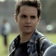 the young man is wearing a plaid shirt and looking at the camera with an angry look on his face