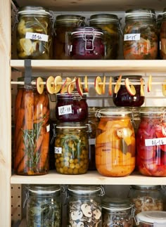 jars filled with pickled vegetables and other foods are on shelves next to each other