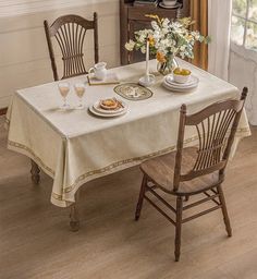 a dining room table with two chairs and a white table cloth on top of it