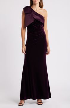 a woman in a long purple dress with one shoulder draped over her shoulders and an asymmetrical neckline