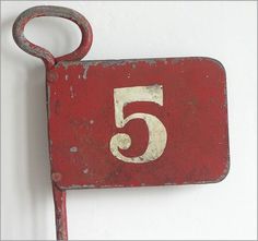 a red sign with the number five hanging from it's side on a white wall