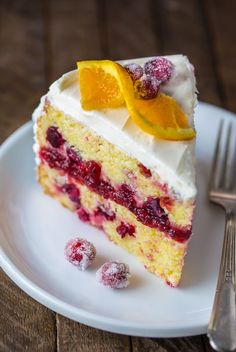 a white plate topped with a piece of cake next to a fork and orange slice