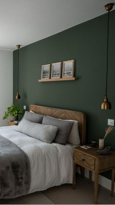 a bedroom with green walls and white bedding, two framed pictures on the wall