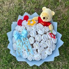 a teddy bear sitting on top of a pile of baby diapers in the grass