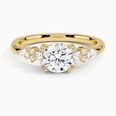 a yellow gold engagement ring with an oval cut diamond surrounded by smaller round brilliant diamonds