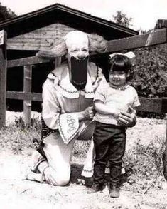 an old black and white photo of two children standing next to a statue of a clown