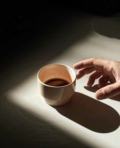 a person's hand reaching for a cup of coffee