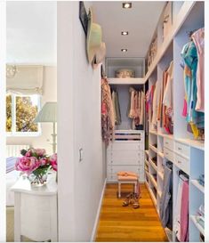 a walk in closet with lots of clothes on shelves and drawers, next to a bed