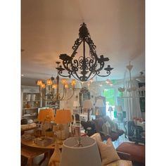 a chandelier hanging from the ceiling in a living room filled with furniture and lamps