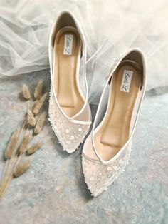 a pair of white shoes sitting on top of a stone floor next to a dried plant