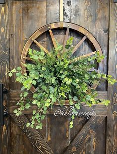 a wooden door with a plant growing in the center and an old wagon wheel hanging on it