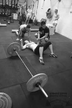 two men are sitting on the ground while one man is holding a barbell