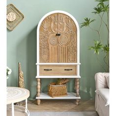 an ornate wooden cabinet in the corner of a room with green walls and white furniture