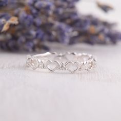 a close up of a ring with hearts on it and lavender flowers in the background