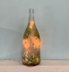 a glass bottle with some lights in it on a shelf next to a wall and floor