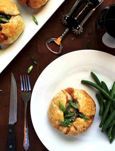 some food is sitting on a white plate next to silverware and wineglasses