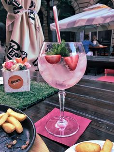 a drink with strawberries in it sitting on a table next to other food items