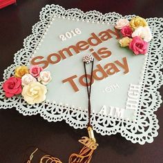 a graduation cap with flowers on it and the words somebody is today written in gold