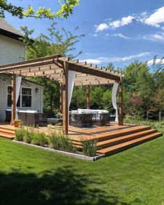 an outdoor patio with wooden steps and pergolated seating area, surrounded by lush green grass