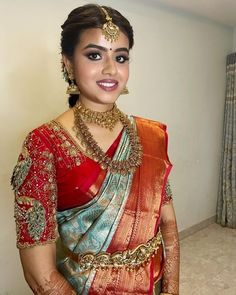 a woman in a red and gold sari with jewelry on her neck posing for the camera