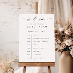 a welcome sign sitting on top of a wooden easer next to a vase filled with flowers